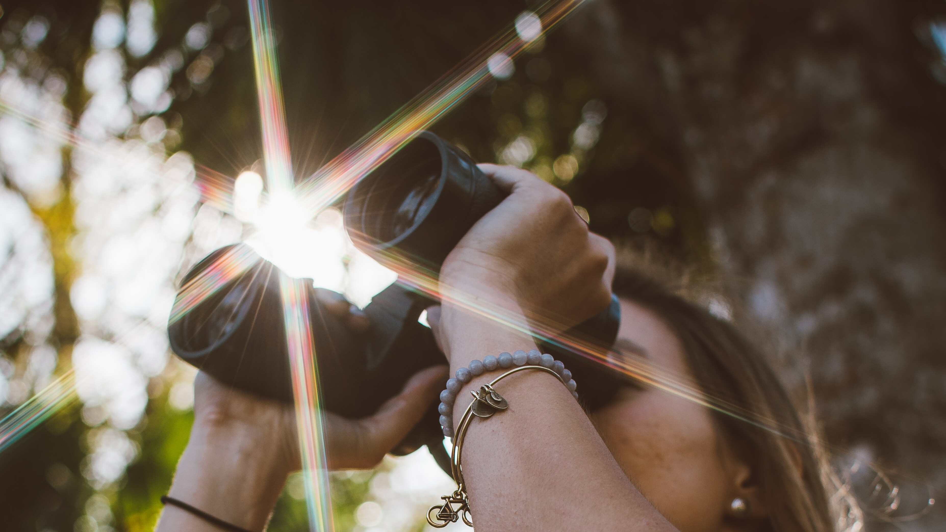 Junge Frau schaut mit Fernglas in die Ferne.