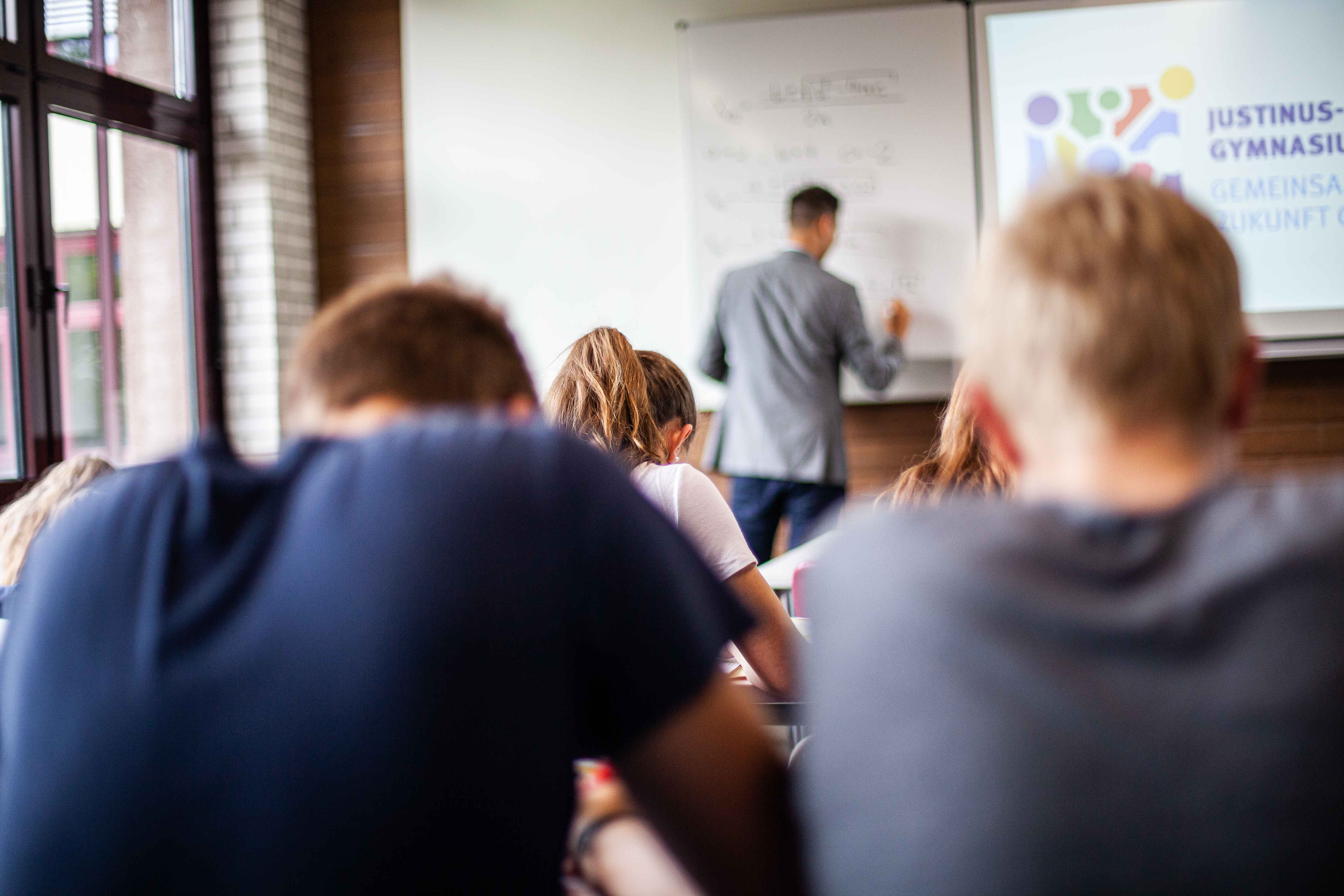 Blick zur Tafel: Schülerinnen und Schüler schreiben den Tafelaufschrieb des Lehrers ab.