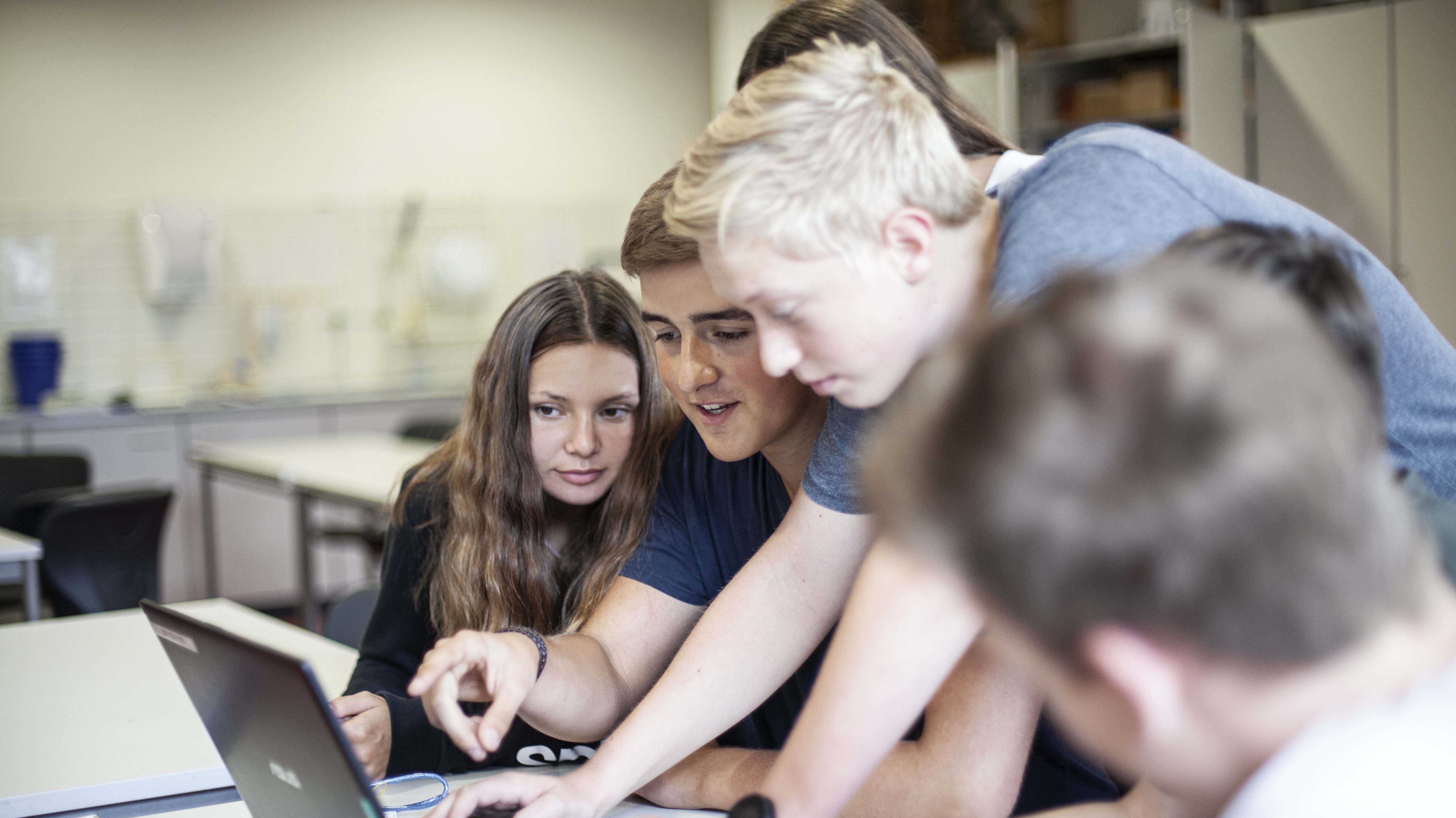 Eine Gruppe von Schülerinnen und Schüler sitzen vor einem Laptop und besprechen sich.